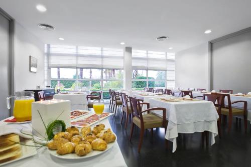 a dining room with tables and chairs with food on them at Hotel Air Penedès in Vilafranca del Penedès