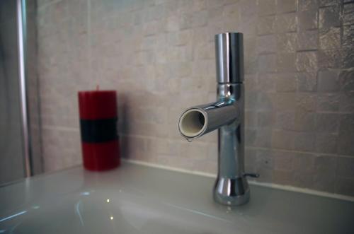 a pipe sitting on top of a sink with a red candle at Hôtel Des Amandiers in Cayenne