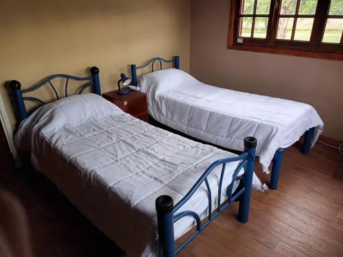 Casa amplia barrio privado Miramar في ميرامار: سريرين توأم في غرفة بها نافذة