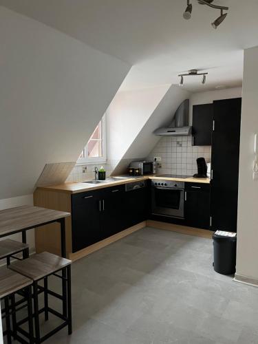 - une cuisine avec des placards noirs, un évier et une table dans l'établissement Appartement de l angle Im Winkel, à Oberbetschdorf