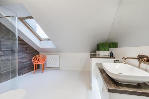 bagno con lavandino e sedia rossa di Langgarten Apartments by Little Heaven a Danzica