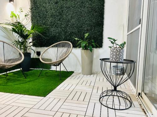 two chairs and a table on a patio with plants at Hortensia rooms in St Paul's Bay