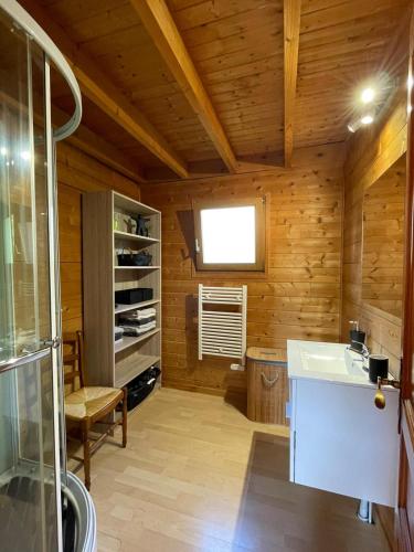 La salle de bains est pourvue de murs en bois, d'un lavabo et d'une fenêtre. dans l'établissement Les Fuchsias, face au lac de Longemer, à Xonrupt-Longemer