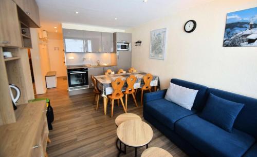 un salon avec un canapé bleu, une table et des chaises dans l'établissement Résidence Le France - 3 pièces 6/7 pers - LE FRANCE - PLAGNE CENTRE MAE-9174, à Aime La Plagne