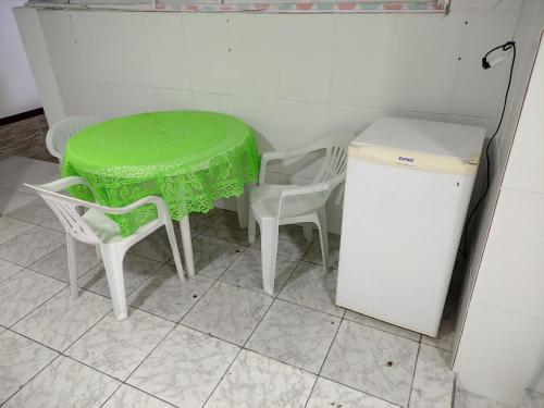 a green table and two chairs and a refrigerator at Excelente APTO proximo ao centro in Itaperuna