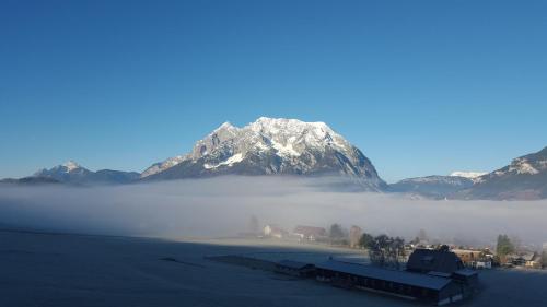 a snow covered mountain in the middle of a foggy field at Ferienwohnung Pichlarn in Aigen im Ennstal