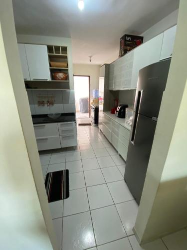 a kitchen with white tile floors and a refrigerator at aconchegante e tranquila in Parnamirim