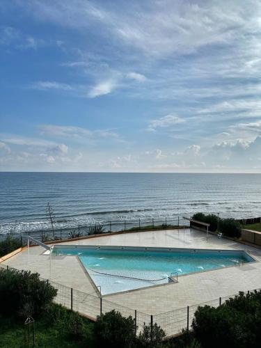 une piscine avec l'océan en arrière-plan dans l'établissement Studio les pieds dans l'eau, à Santa-Lucia-di-Moriani