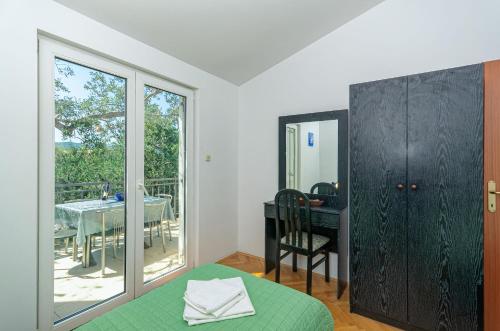 a bedroom with a green bed and a table with a balcony at Apartments Franka in Klek