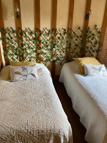 deux lits dans une chambre avec un mur dans l'établissement Escapade Normande, à Yerville