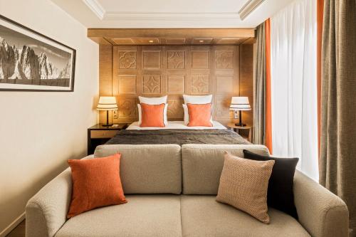 a bedroom with a bed and a couch with pillows at Hôtel Mont-Blanc Chamonix in Chamonix-Mont-Blanc