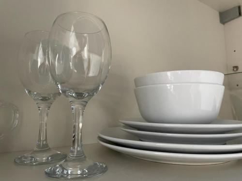 two wine glasses and plates on a table at La Ferme du Château - Studio 1 in Fontaine-lʼÉvêque