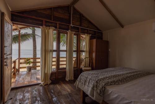 a bedroom with a bed and a view of the ocean at Ravi Yoga Retreat in Polem