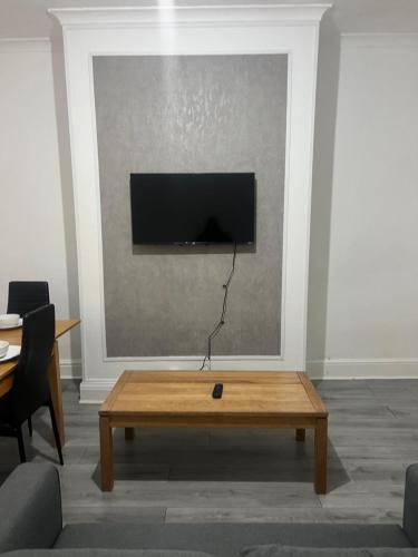 a living room with a table and a tv on a wall at Alton House in Hollinwood