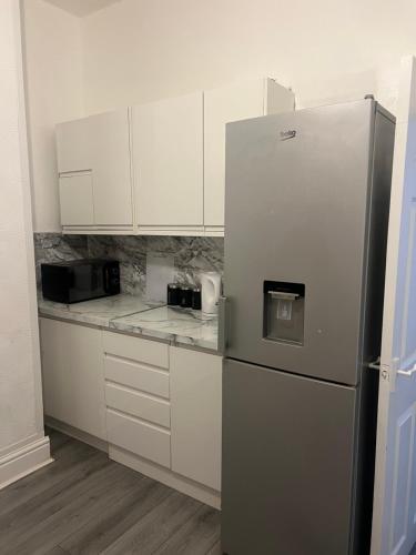 a kitchen with a refrigerator and white cabinets at Alton House in Hollinwood