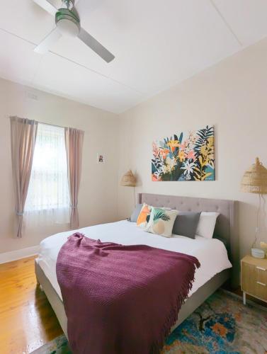 a bedroom with a large bed with a purple blanket at Clare Cottage with 3 King Suites in Clare