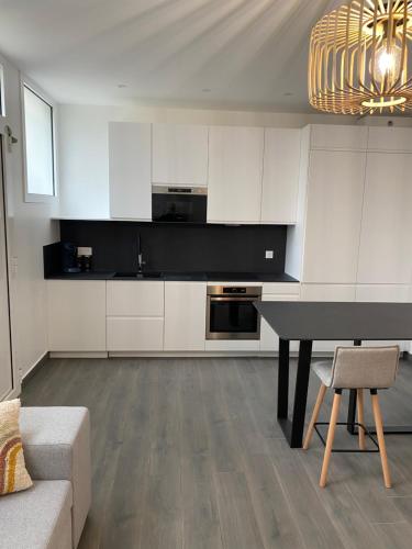 une cuisine avec des placards blancs et une table noire dans l'établissement Appartement Cosy entre Paris et Disney, à Villiers-sur-Marne