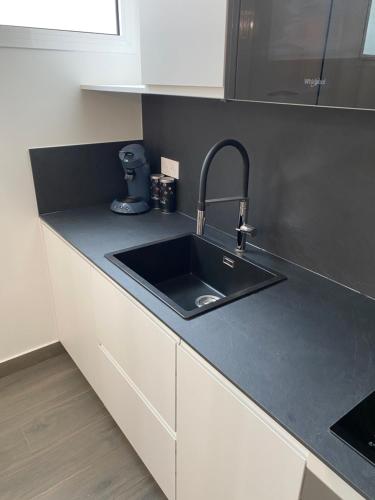 - un évier de cuisine avec un plan de travail noir dans l'établissement Appartement Cosy entre Paris et Disney, à Villiers-sur-Marne