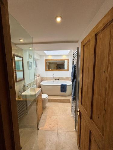 a bathroom with a tub and a toilet and a sink at Mellow Cottage just a short walk to the beach in Perranporth