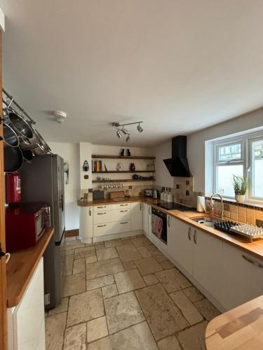 a large kitchen with white cabinets and a tile floor at Mellow Cottage just a short walk to the beach in Perranporth