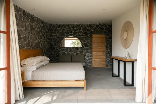 a bedroom with a bed and a stone wall at Casa Chavela in Tepoztlán