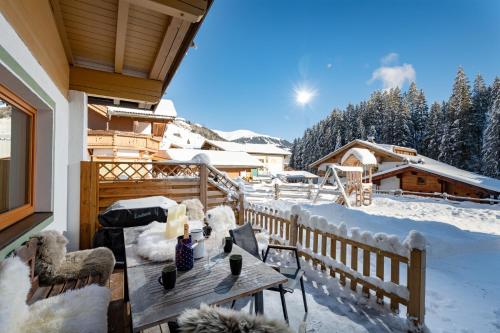 a wooden deck with a table and chairs in the snow at Anja's Schönblick - Bed & Breakfast in Gerlos