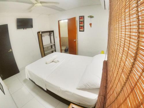 a bedroom with a white bed with a ceiling fan at Cristal Tayrona in Los Naranjos