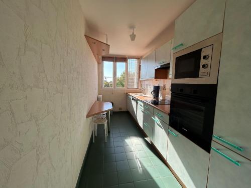 une cuisine avec une cuisinière et un micro-ondes dans l'établissement Appartement lumineux 3 chambres à Tours nord, à Tours