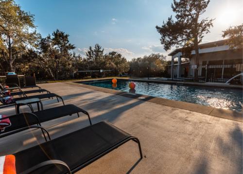 una piscina con bancos junto a un edificio en The Liney Moon, en Dripping Springs