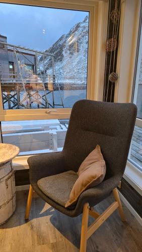 a chair with a pillow sitting in front of a window at Hemmingodden Lodge in Ballstad