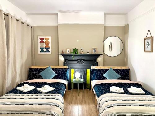 two beds in a room with a fireplace at Delux Rooms Near City Centre in London