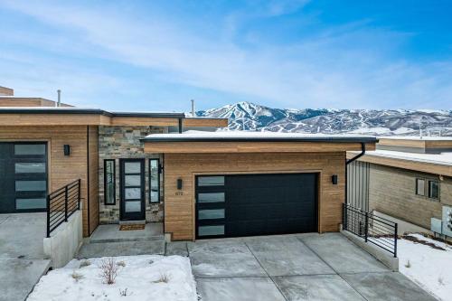 a house with a garage with mountains in the background at Luxury Lakeview Retreat A Jordanelle Gem in Hideout, Utah in Keetley