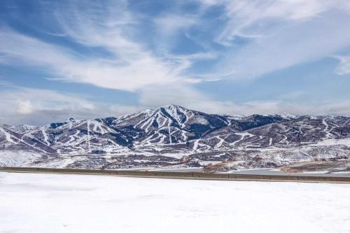 a view of a snowy mountain range with a train at Luxury Lakeview Retreat A Jordanelle Gem in Hideout, Utah in Keetley