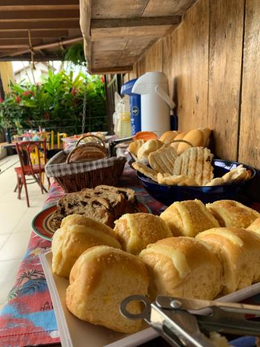 a table with plates of bread and bowls of pastries at Pousada Casa Guntzel Juquehy - Piscina e ar condicionado in Juquei