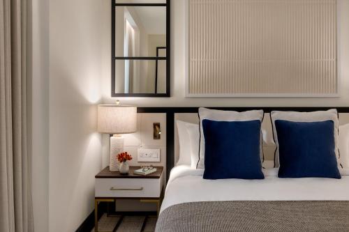 a bedroom with a bed with blue pillows and a mirror at The Chemists Club Hotel in New York