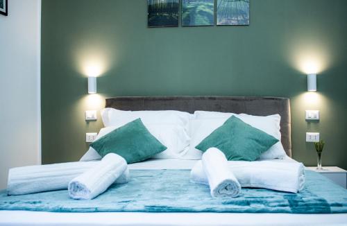 a bed with white sheets and green pillows on it at Green Garden in Rome