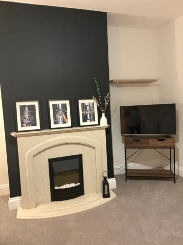 a living room with a fireplace and a flat screen tv at Cross Street in Oswaldtwistle