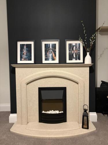a living room with a fireplace with pictures on the wall at Cross Street in Oswaldtwistle