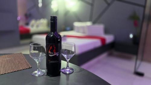 a bottle of wine and two wine glasses on a table at MOTEL COPACABANA in Ribeirão Preto