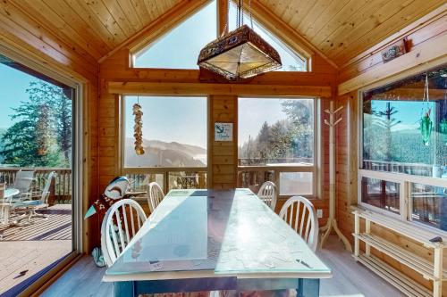 a dining room with a table and chairs and windows at The Magical Forested Sea Cove in Carpenterville