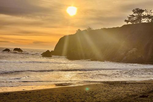 a beach with the sun shining on the water at The Magical Forested Sea Cove in Carpenterville