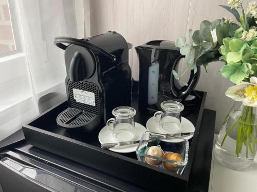 a coffee maker and cups on a black tray at La Ferme du Château - Classic Room in Fontaine-lʼÉvêque