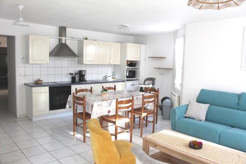 Il comprend une cuisine et un salon avec une table et un canapé bleu. dans l'établissement Appartement T3 classé trois étoiles au calme de plain-pied au centre Doussard avec vue sur montagne, lac Annecy à proximité, à Doussard