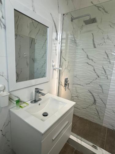 a white bathroom with a sink and a shower at Beachtown Luxury Villas Apt 204 in Aguacate