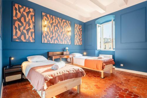 Cette chambre bleue comprend 2 lits et une fenêtre. dans l'établissement Escale Capucines - 3 chambres doubles 95 m2 décoré chic et élégant idéal groupes, à La Ciotat