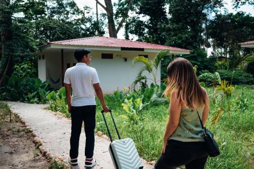 a man and a woman standing outside a house with a suitcase at Taki Tambo Lodge in Tarapoto