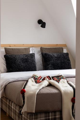 a bed with blankets and pillows on top of it at Panocek i Babka in Białka Tatrzanska