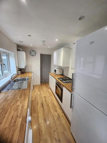 a kitchen with a white refrigerator and a wooden floor at Manor House walsall 3 in Walsall