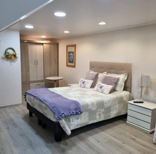 a bedroom with a large bed with purple sheets and pillows at Habitaciones Dobles Valdivia, Isla Teja in Valdivia