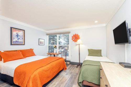 a bedroom with two beds and a flat screen tv at Mountainside Inn 103 by Alpine Lodging Telluride in Telluride